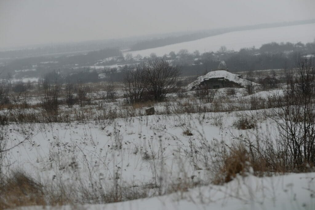 A rifle bunker juts out in a snowy field.