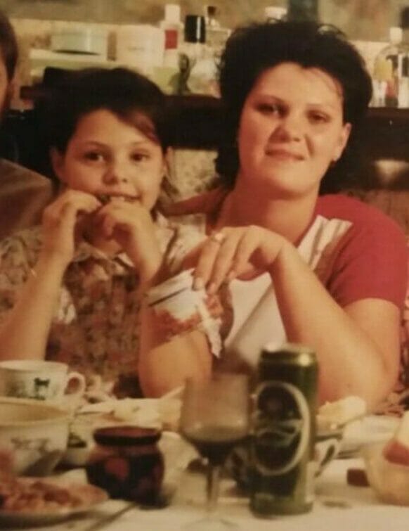 Eine alte Aufnahme: Ein Mädchen, Jules, und eine Frau, ihre ältere Schwester Zhanna lächeln in die Kamera.