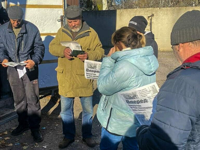 Bewohner:innen in Bachmut lesen eine Ausgabe der Wochenzeitung 