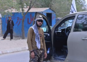 Ein Mann mit Kopftuch steht neben einem Auto.