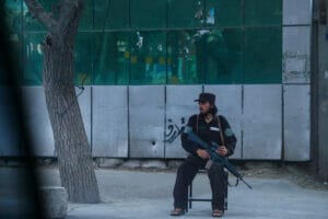 Ein Mann sitzt auf einem Stuhl neben einem Baum.