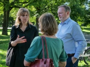 Drei Personen unterhalten sich in einer ruhigen Parkumgebung.