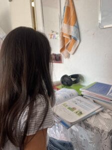 A girl sitting at a table looking at books.