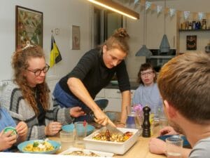 Jenny schneider die Quiche an und verteilt am Esstisch die Portionen.