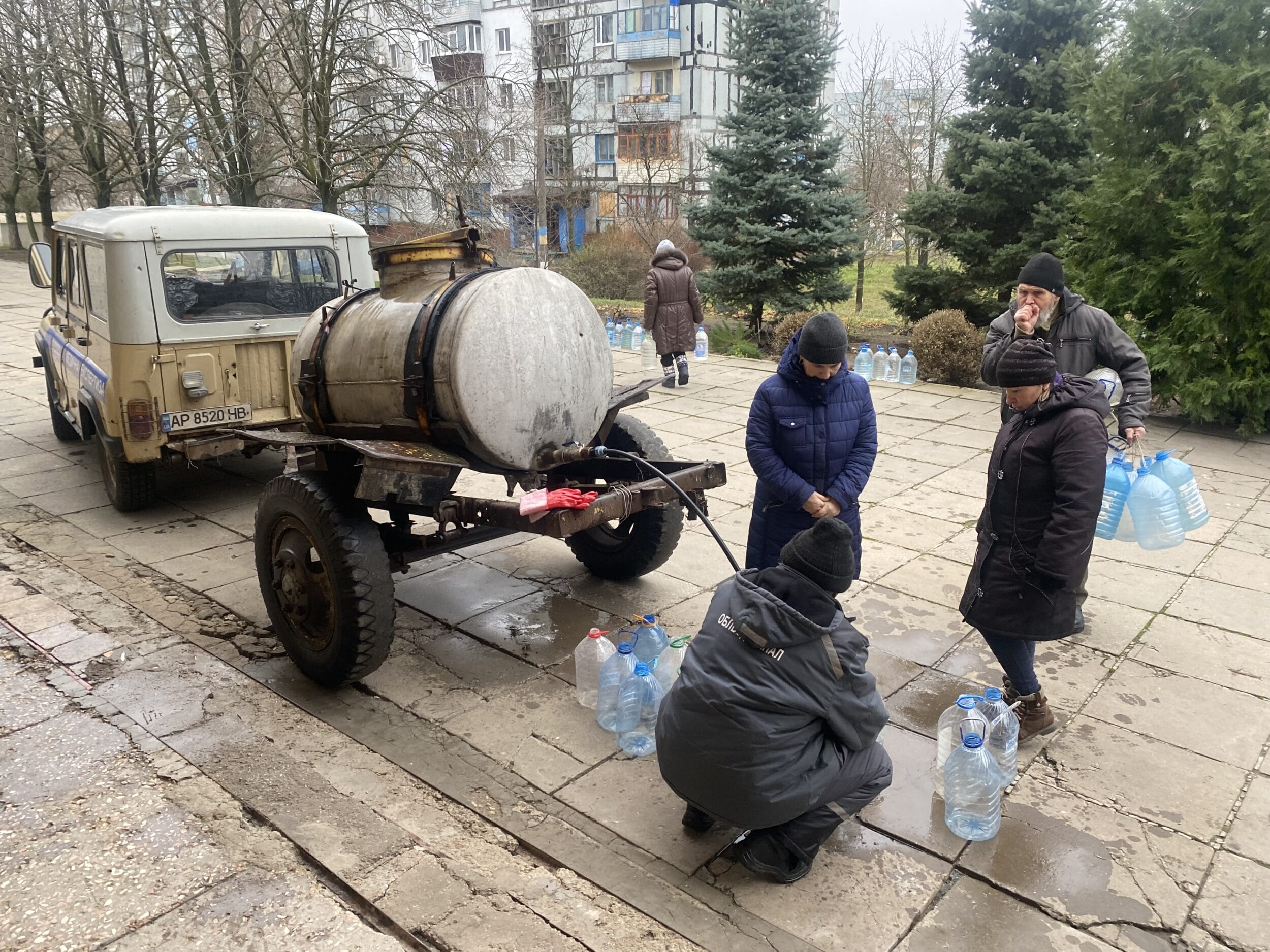 Eine Gruppe von Menschen steht neben einem Lastwagen mit Wasserflaschen.