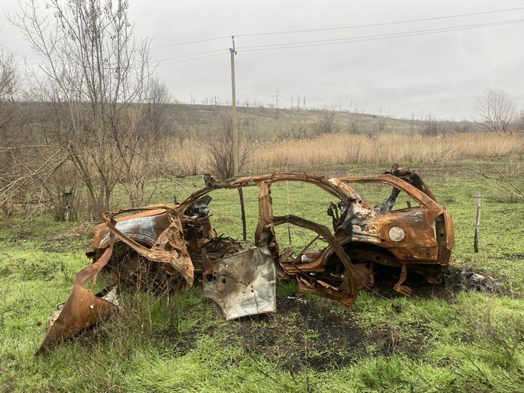 Ein verrostetes Auto steht mitten auf einem Feld.