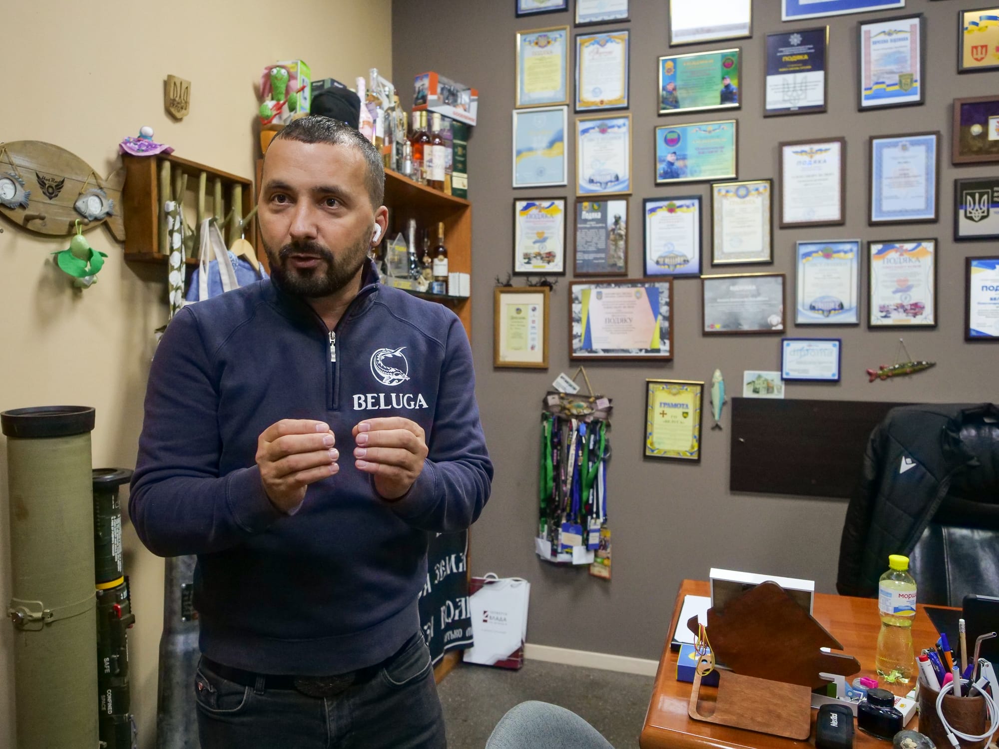 Oleksandr Beluga steht vor seinem Schreibtisch. An der Wand dahinter sind viele Auszeichnungen für ihn und seine NGO zu sehen.
