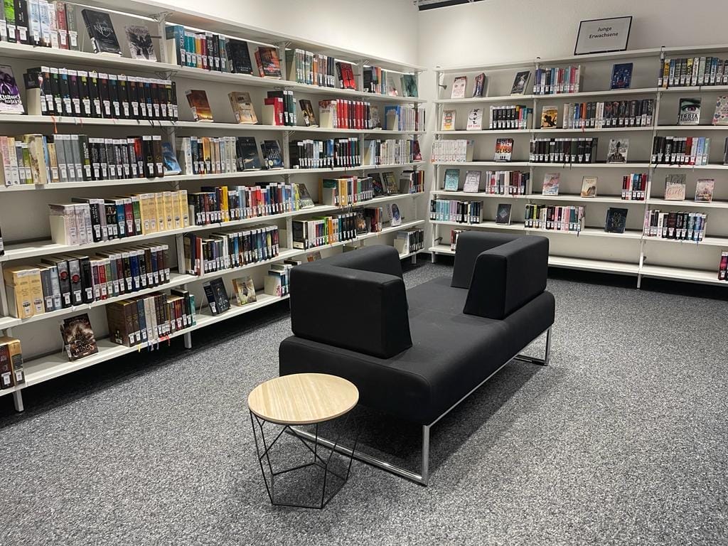 Eine Bibliothek mit einer schwarzen Couch und Bücherregalen.