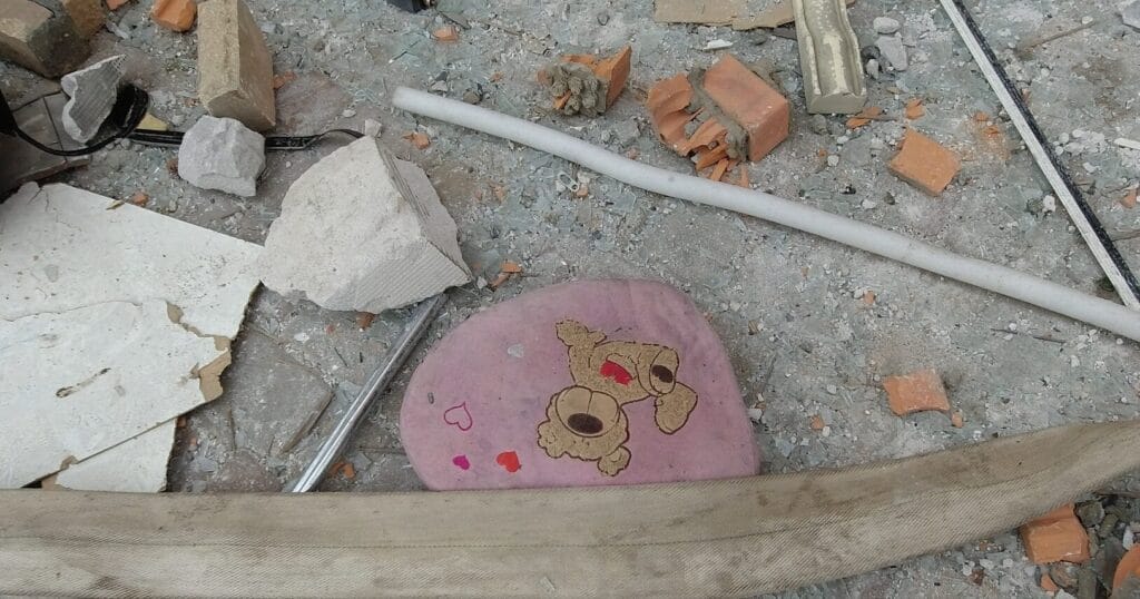 Ein weggeworfenes Kissen mit einem Cartoon-Gesicht inmitten von Bauschutt und Materialien.