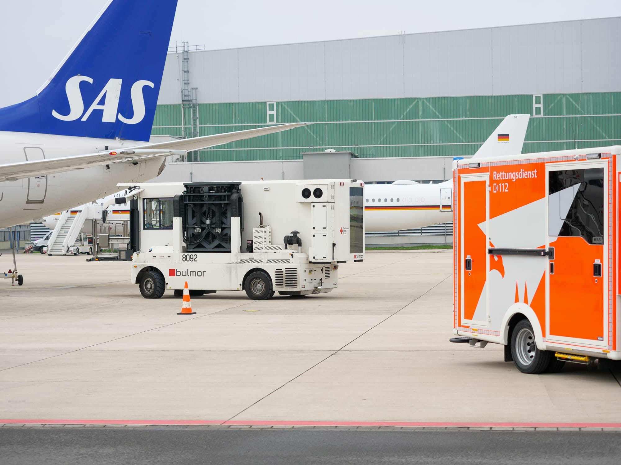 Bodenunterstützungsfahrzeuge warten ein SAS-Flugzeug auf einem Flughafen.