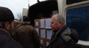 Männer stehen neben einem mit Kartons beladenen Lieferwagen.