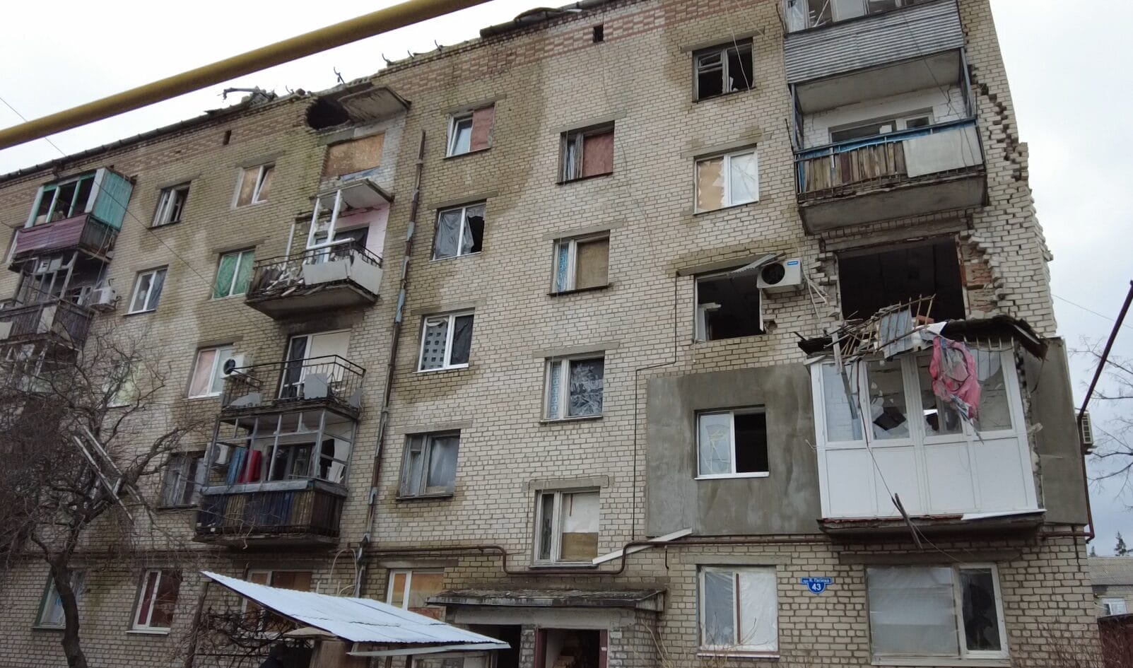 Beschädigtes Wohnhaus in Lyman mit zerbrochenen Fenstern und Trümmern, die auf Zerstörung hinweisen.
