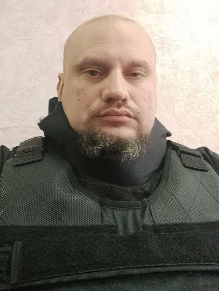 Sergey Panashchuk trägt eine schwarze kugelsichere Weste und schaut in die Kamera.